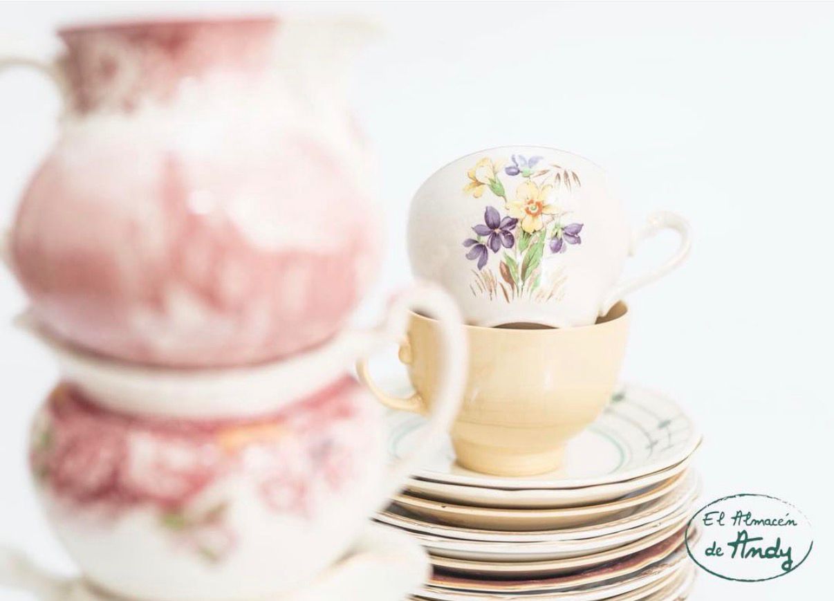 Jarra rosa antigua junto a tazas de porcelana floral