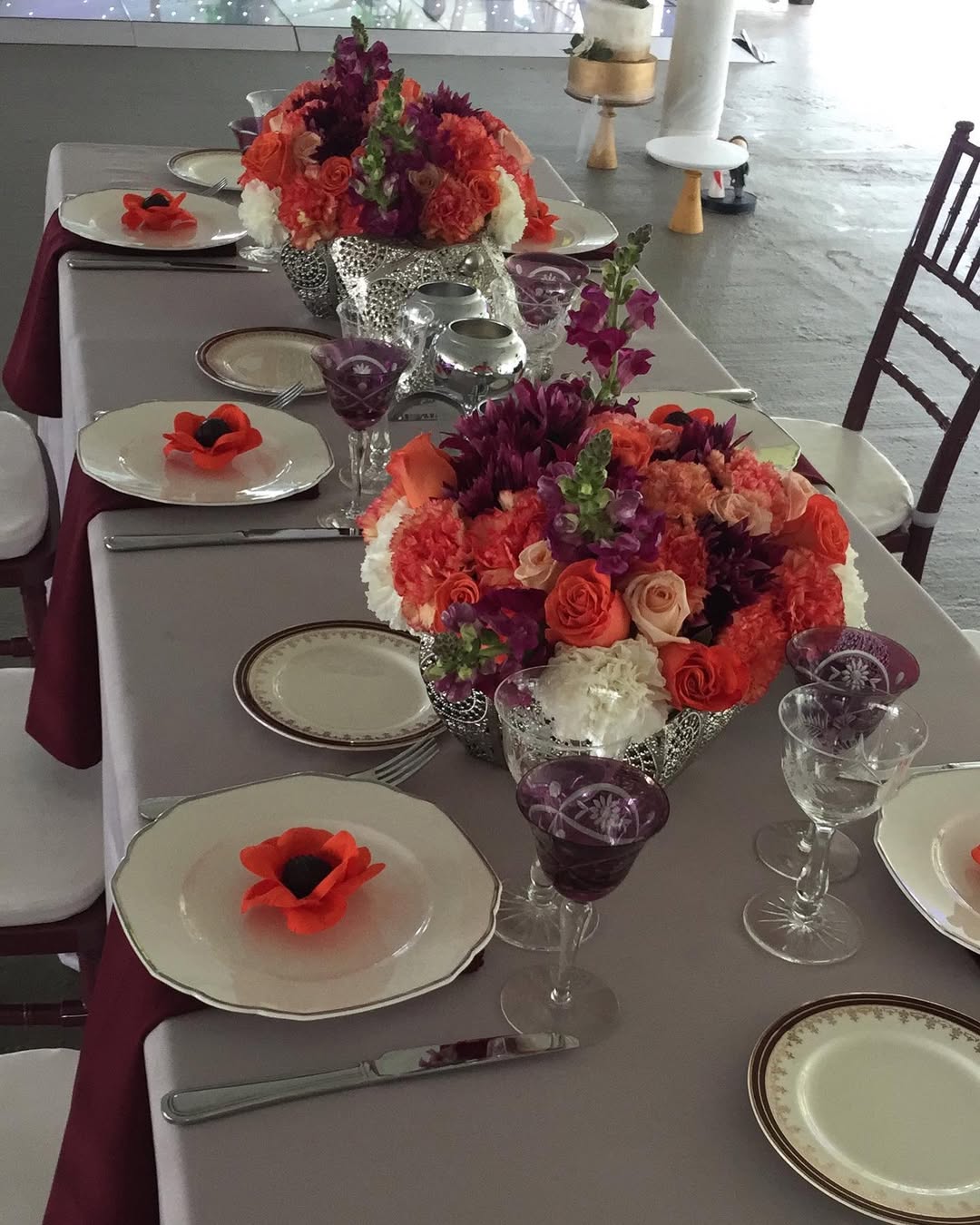 Mesa de fiesta con centros florales coloridos y copas de cristal violeta
